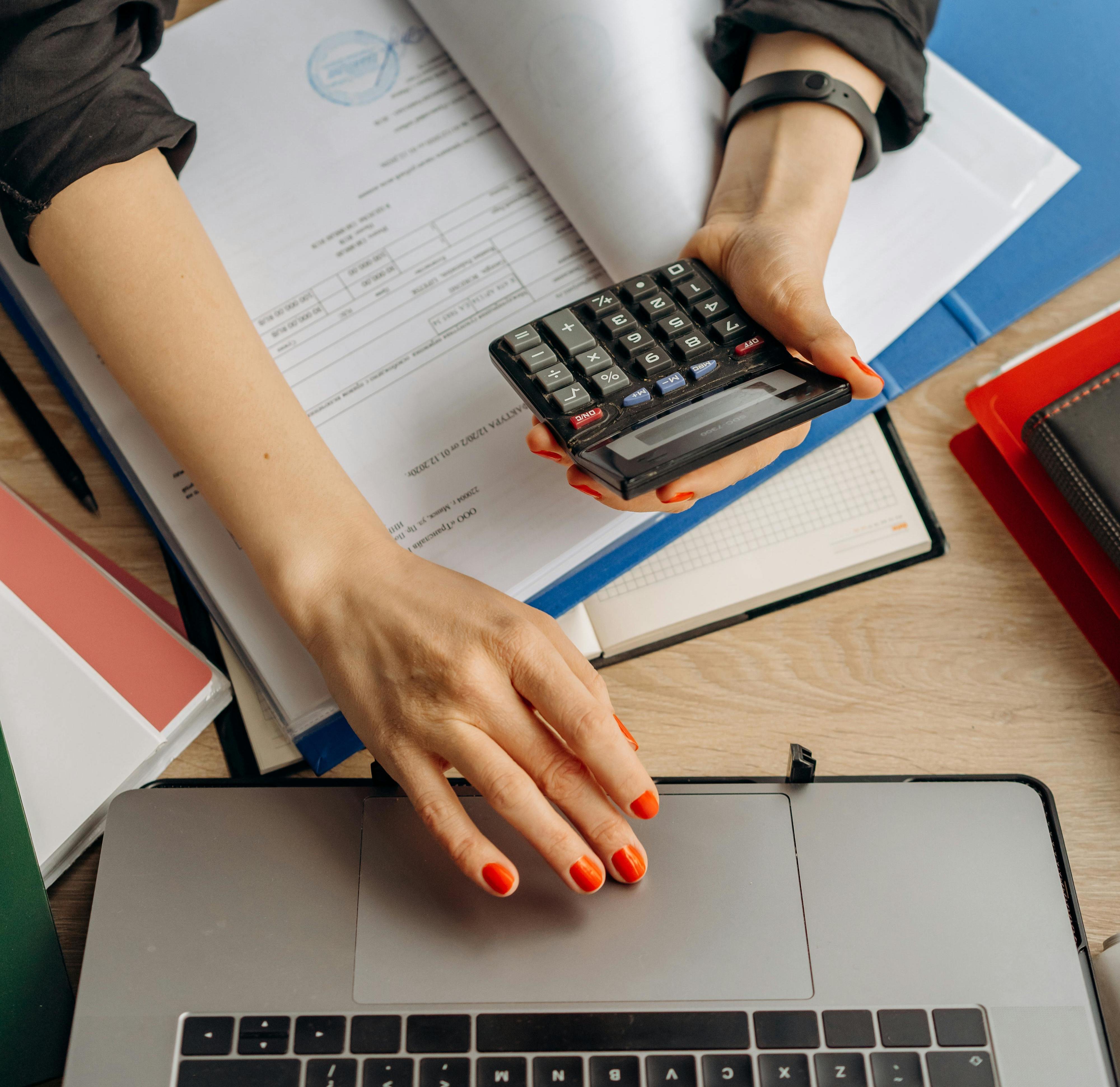 image of desk with laptop, forms, notes, and a calculator on it